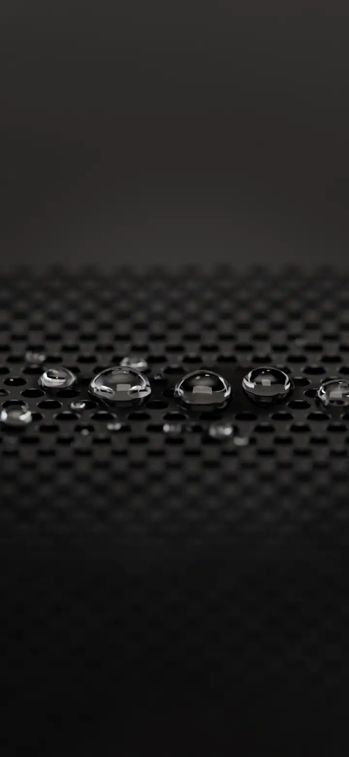 Water beads sitting in the holes of a metal speaker grille
