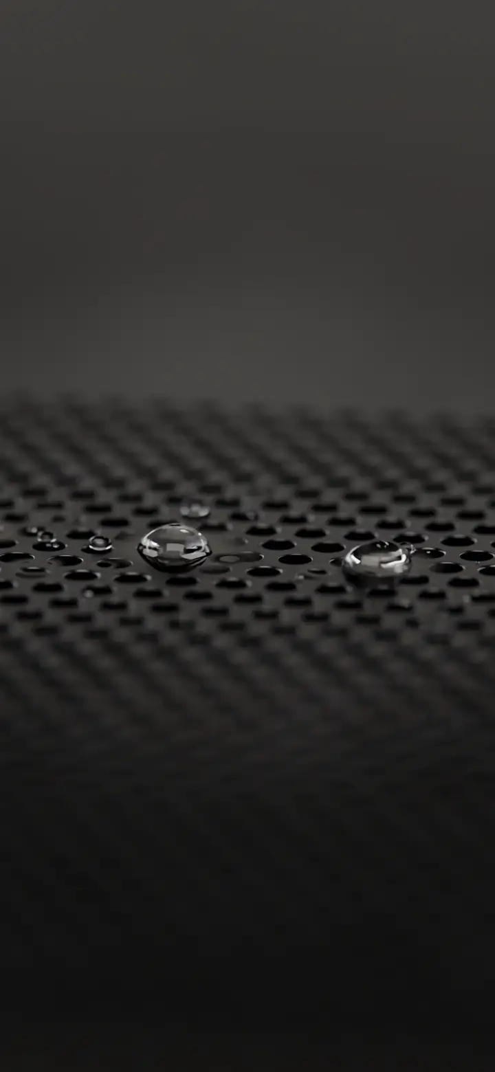 A metal speaker grille with a few small water droplets left behind