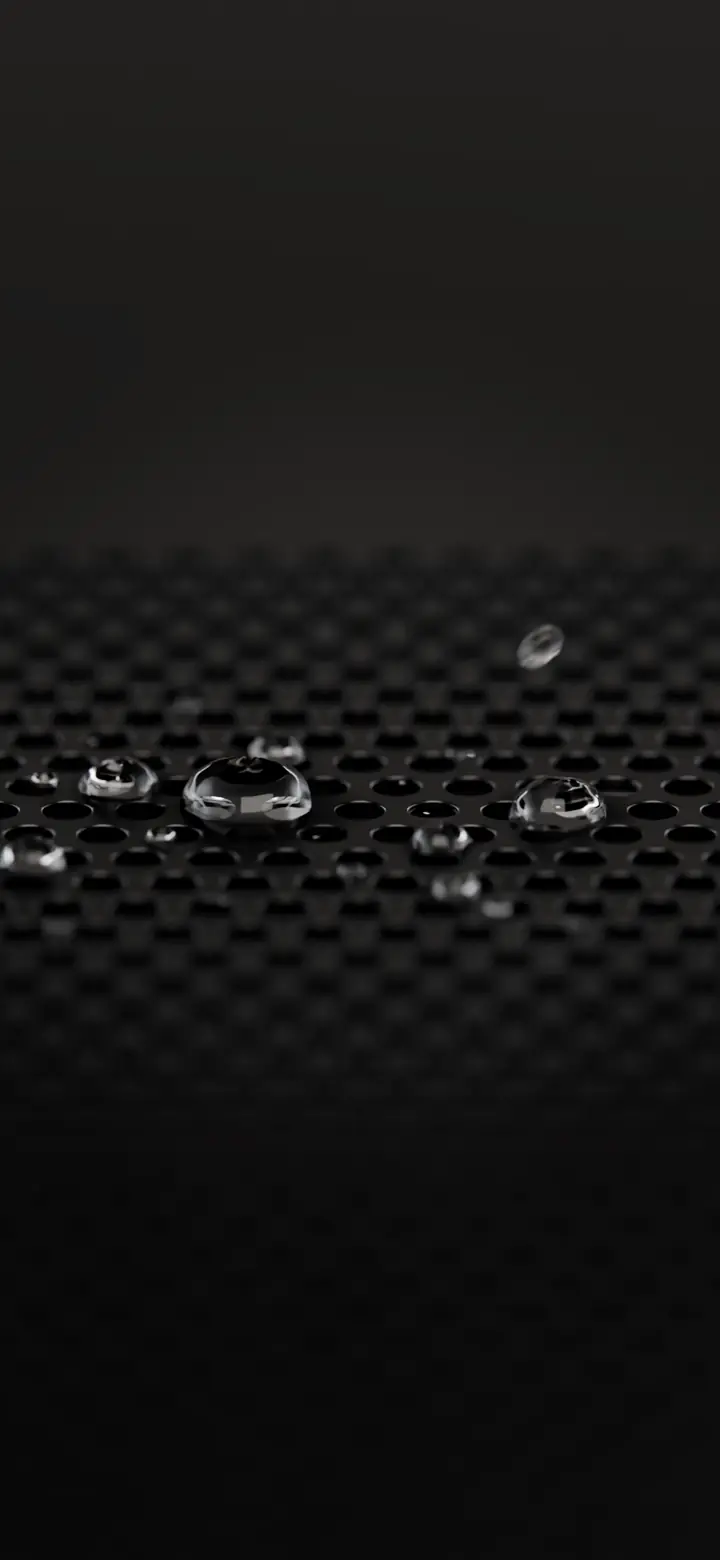 Macro of water beads resting on the holes of a dark metal speaker grille